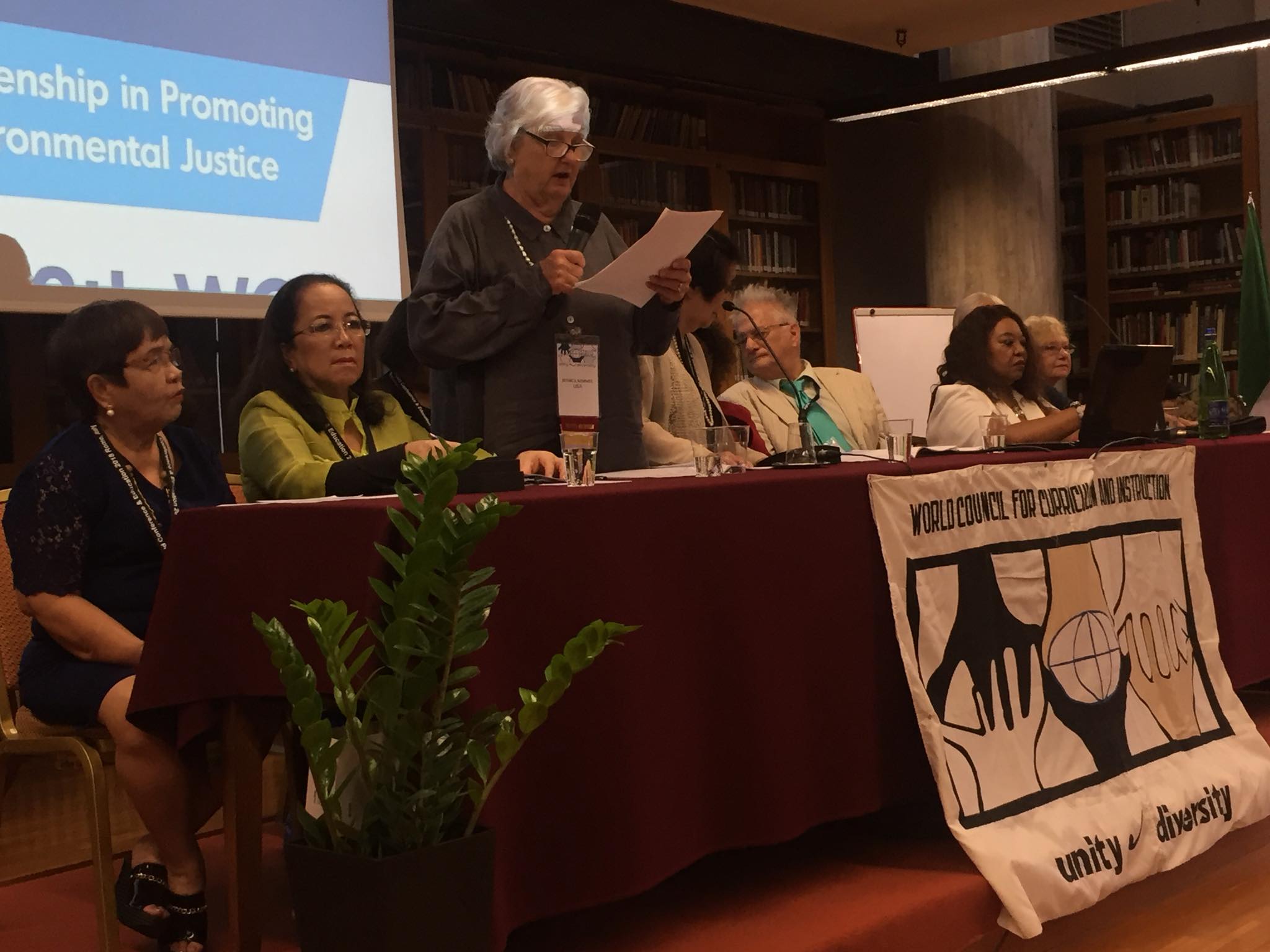Back of a man at a concert. Hes wearing a beanie hat and a baggy denim jacket with studs. Photo with a purple hue
